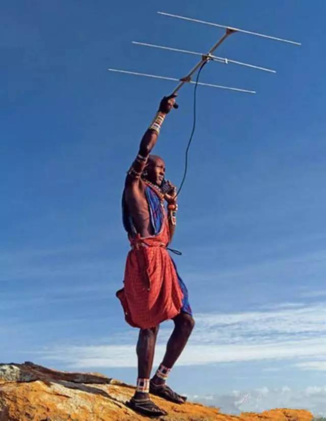 图为一位非洲部落男子正举着天线在打电话.