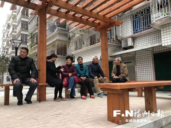 居民围坐在小区内新建的花架下聊天.