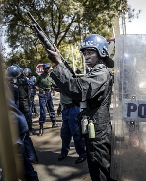 zimbabwean anti-riot police officers stand guard and close the